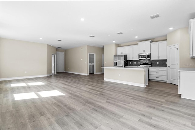 1973 E Celina St, Inverness, FL 34453 - kitchen featuring appliances with stainless steel finishes, open floor plan, a kitchen island with sink, light wood-style floors, and backsplash