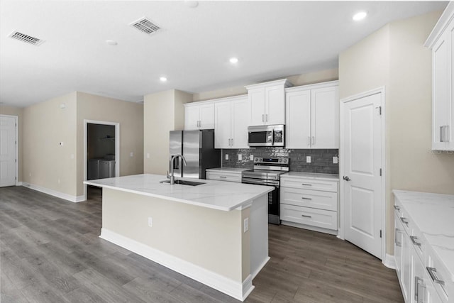 1973 E Celina St, Inverness, FL 34453 - kitchen featuring appliances with stainless steel finishes, washing machine and dryer, a sink, a kitchen island with sink, and tasteful backsplash