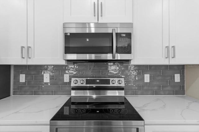1973 E Celina St, Inverness, FL 34453 - kitchen with stainless steel appliances, white cabinetry, backsplash, and light stone countertops