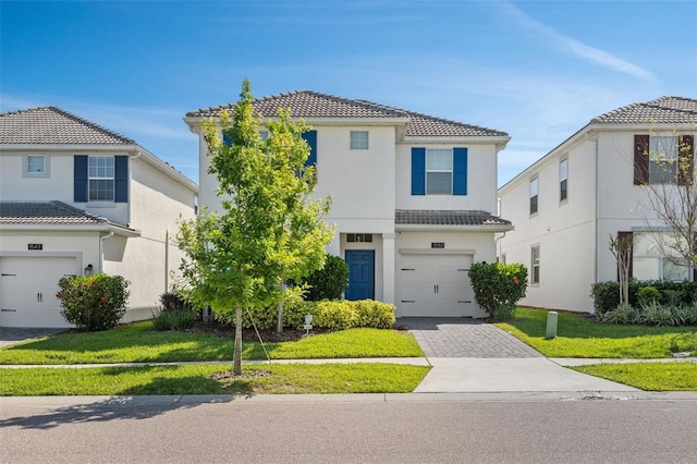 1551 Flange Dr, Davenport, FL 33896 - view of front of house featuring a front lawn, a tiled roof, stucco siding, decorative driveway, and an attached garage