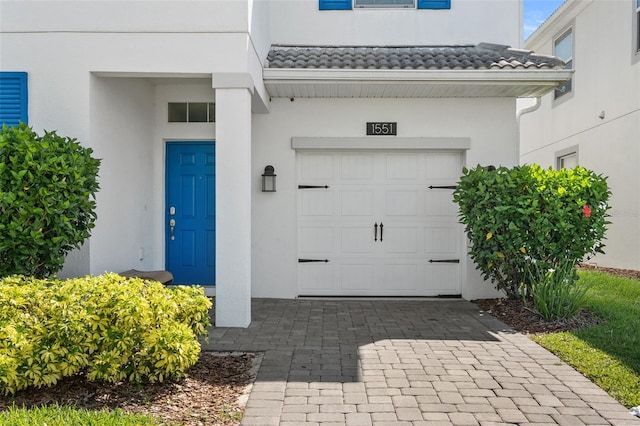 1551 Flange Dr, Davenport, FL 33896 - view of exterior entry with a tile roof, an attached garage, driveway, and stucco siding
