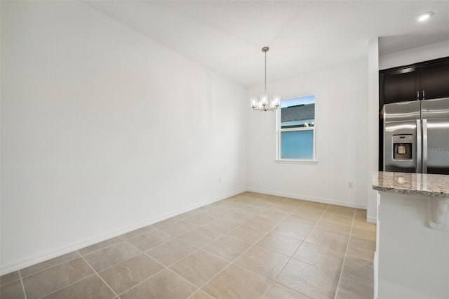 unfurnished dining area with light tile patterned floors, a notable chandelier, and baseboards