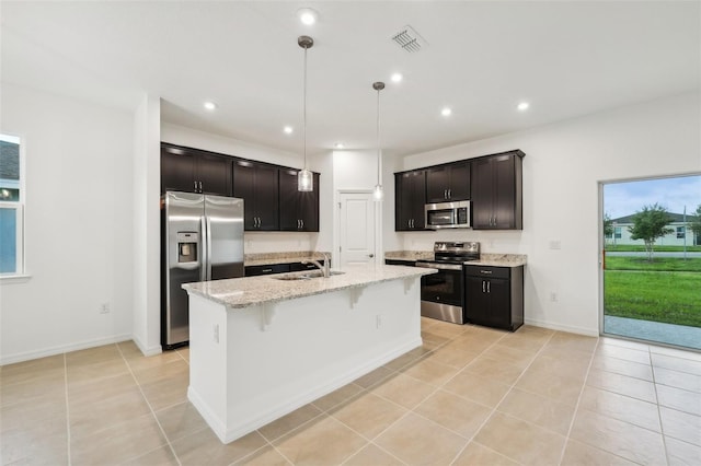 kitchen featuring visible vents, a breakfast bar, a sink, appliances with stainless steel finishes, and light stone countertops