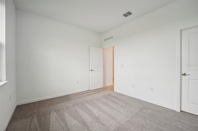 carpeted spare room with visible vents and baseboards