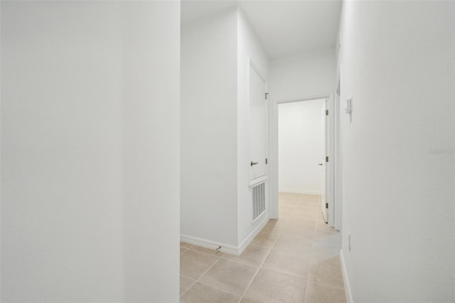 hallway featuring light tile patterned floors, visible vents, and baseboards