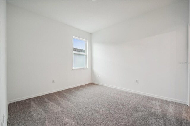 empty room featuring baseboards and carpet