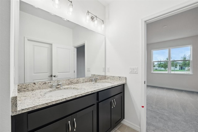 bathroom featuring double vanity, baseboards, and a sink