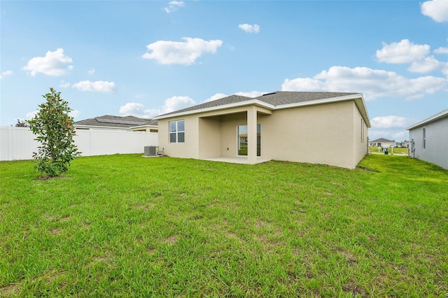rear view of house featuring stucco siding, a lawn, and fence