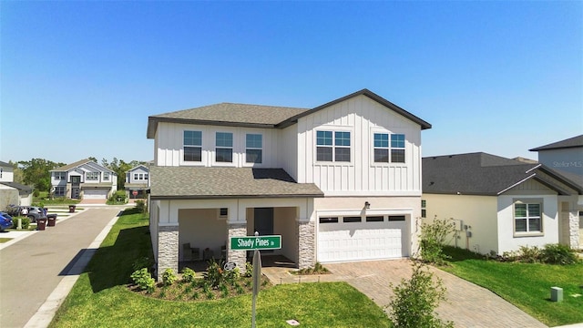 4911 Shady Pines Dr, Saint Cloud, FL 34772 - view of front of property with board and batten siding, a garage, decorative driveway, stone siding, and a front lawn