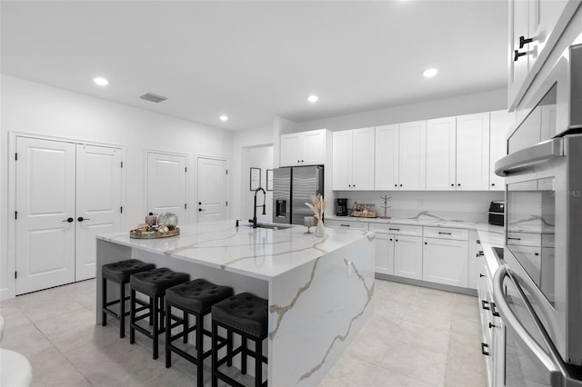 4911 Shady Pines Dr, Saint Cloud, FL 34772 - kitchen with stainless steel appliances, a sink, a center island with sink, white cabinets, and recessed lighting