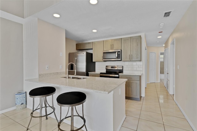 2007 Royal Bay Blvd Unit 144, Kissimmee, FL 34746 - kitchen featuring a kitchen breakfast bar, appliances with stainless steel finishes, a sink, backsplash, and light tile patterned floors