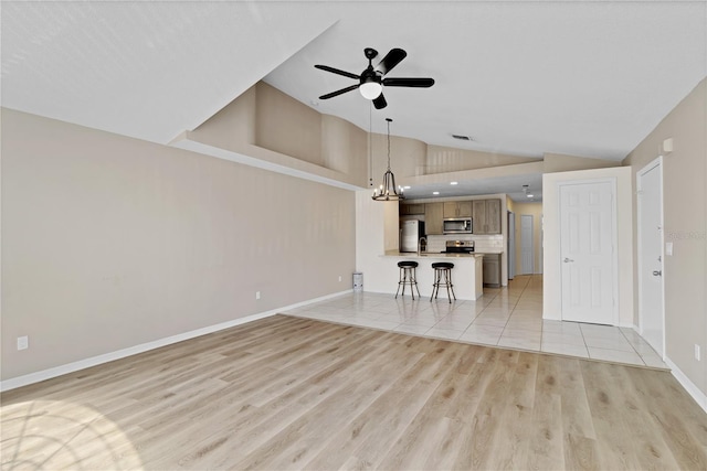 2007 Royal Bay Blvd Unit 144, Kissimmee, FL 34746 - unfurnished living room with light wood-style flooring, high vaulted ceiling, ceiling fan with notable chandelier, and baseboards