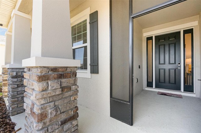 property entrance with stucco siding and covered porch