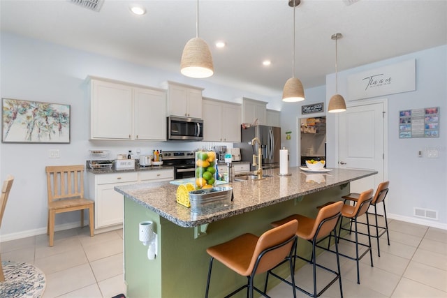 kitchen with a sink, visible vents, a kitchen breakfast bar, and appliances with stainless steel finishes