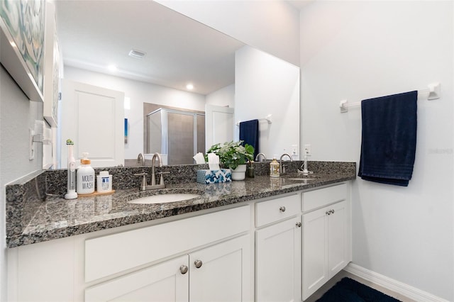 full bathroom featuring a shower stall, double vanity, baseboards, and a sink