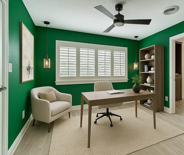 office area with a textured ceiling, baseboards, visible vents, wood finished floors, and ceiling fan