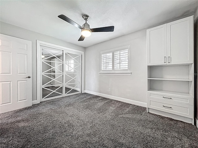 unfurnished bedroom with dark colored carpet, baseboards, and ceiling fan