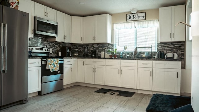 345 W Seminole Ave, Eustis, FL 32726 - kitchen featuring stainless steel appliances, backsplash, white cabinetry, a sink, and dark stone counters