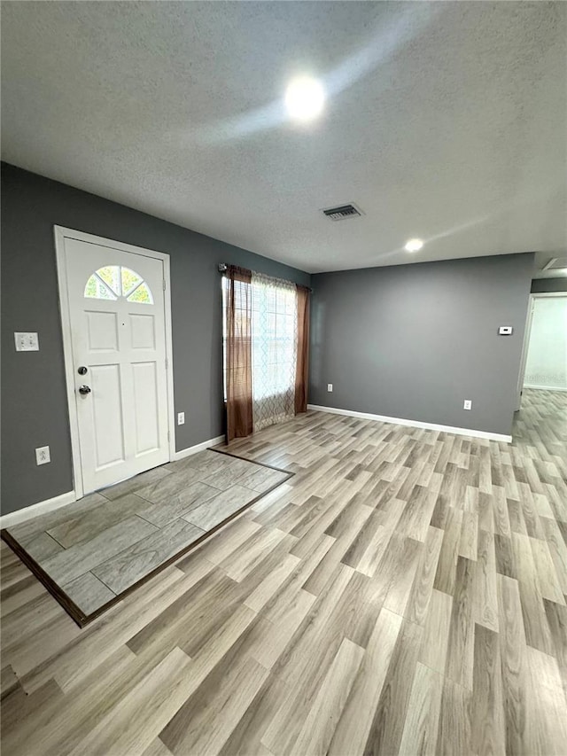345 W Seminole Ave, Eustis, FL 32726 - entryway with healthy amount of natural light, light wood-style flooring, a textured ceiling, and baseboards