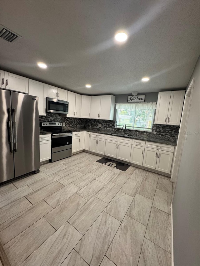 345 W Seminole Ave, Eustis, FL 32726 - kitchen featuring stainless steel appliances, a sink, tasteful backsplash, dark countertops, and white cabinetry