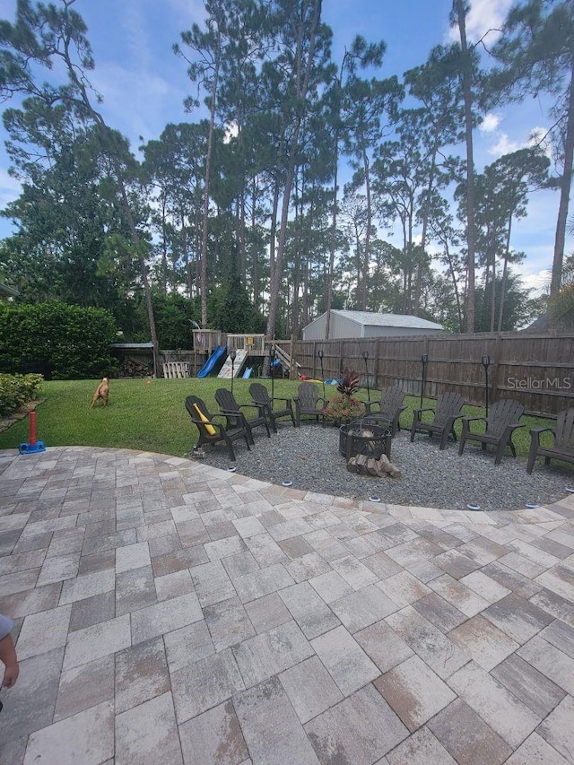 view of patio with an outdoor fire pit, fence, and a playground