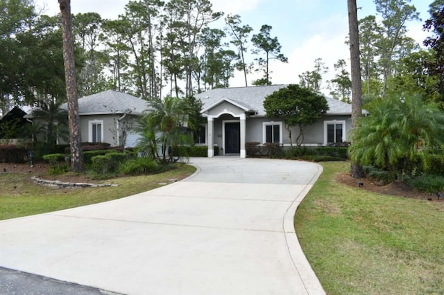 single story home featuring curved driveway, a front yard, and stucco siding