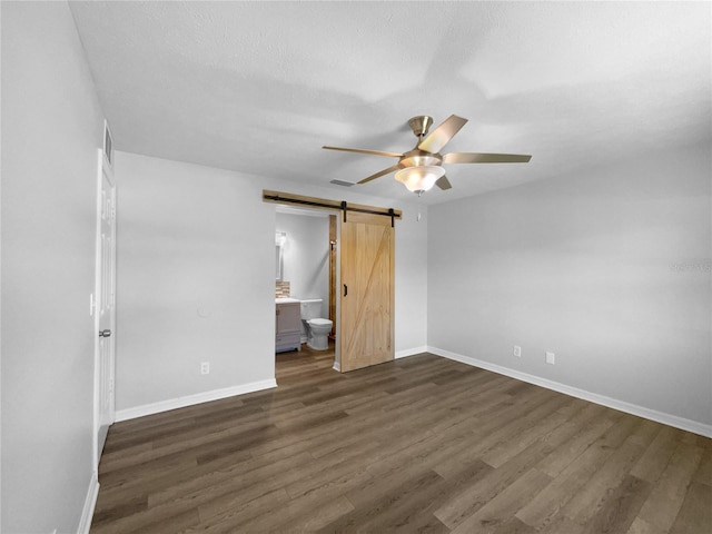 6 Almond Trce, Ocala, FL 34472 - unfurnished bedroom with connected bathroom, baseboards, a barn door, and dark wood-style flooring