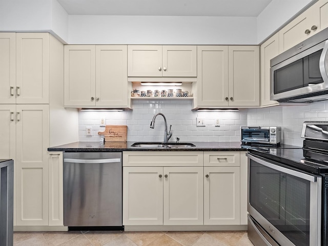 kitchen with tasteful backsplash, a toaster, dark stone counters, stainless steel appliances, and a sink