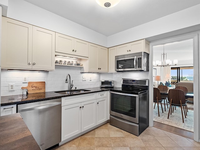 kitchen featuring a chandelier, a sink, backsplash, and stainless steel appliances