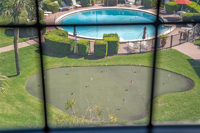 view of property's community with a swimming pool, a yard, and fence