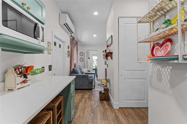 407 E Jersey St, Orlando, FL 32806 - kitchen featuring a wall mounted air conditioner, green cabinets, light countertops, white microwave, and dark wood-style flooring