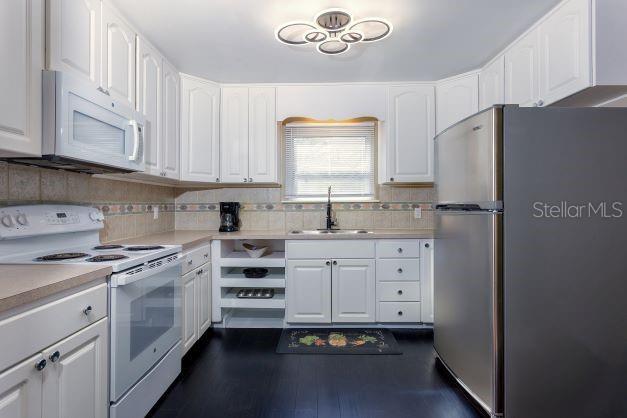 407 E Jersey St, Orlando, FL 32806 - kitchen with white appliances, dark wood finished floors, a sink, light countertops, and white cabinetry
