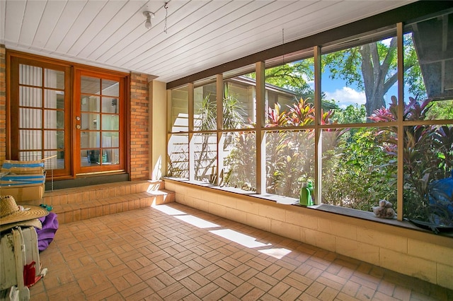 unfurnished sunroom featuring brick floor, french doors, and wooden ceiling