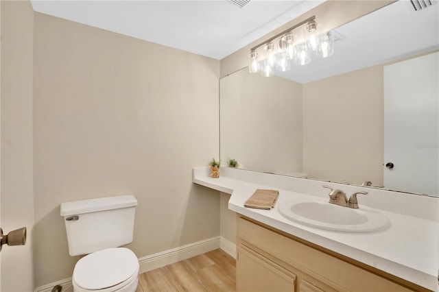 bathroom featuring vanity, wood finished floors, visible vents, baseboards, and toilet