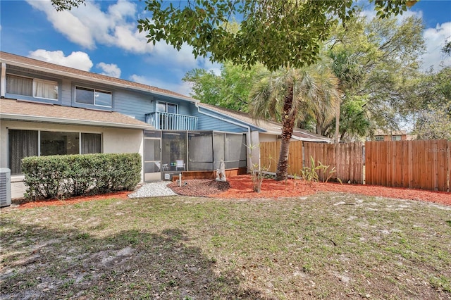 back of house featuring a shingled roof, fence, cooling unit, a yard, and a sunroom