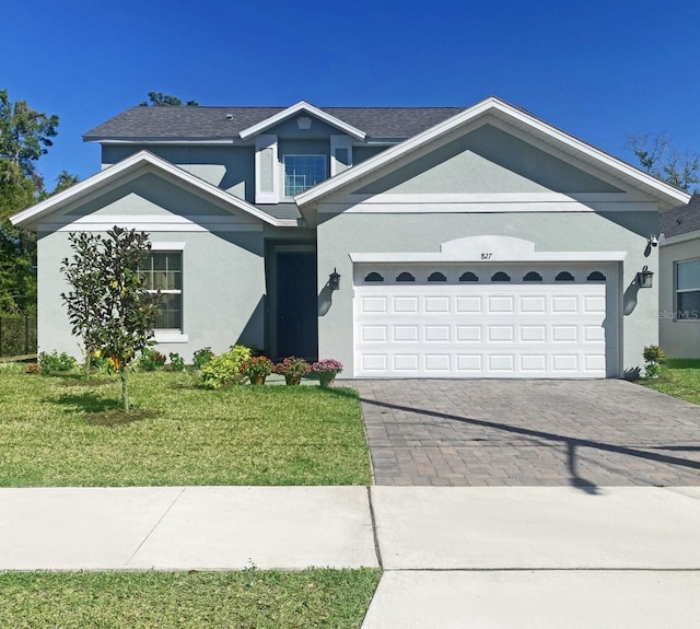 view of front of home featuring decorative driveway, a garage, a front lawn, and stucco siding