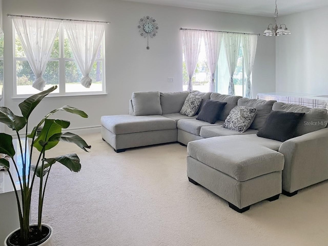 living room featuring carpet flooring, a healthy amount of sunlight, and an inviting chandelier