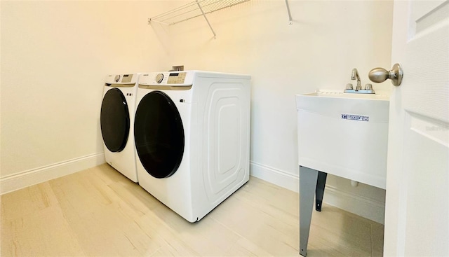 laundry room with laundry area, washing machine and dryer, baseboards, and light wood finished floors