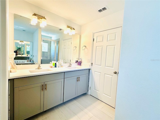 ensuite bathroom featuring double vanity, visible vents, a shower stall, and a sink