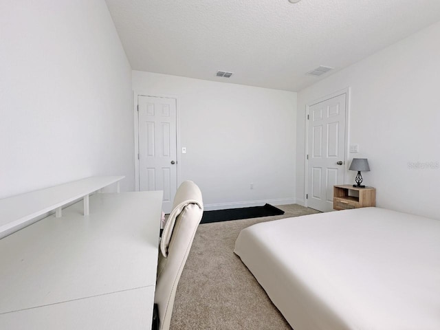 carpeted bedroom with visible vents, a textured ceiling, and baseboards