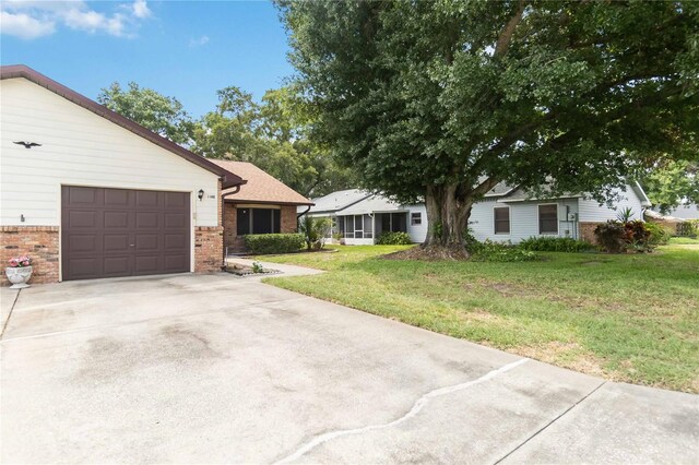 1148 Monroe Ave, Saint Cloud, FL 34769 - single story home featuring brick siding, a front lawn, an attached garage, and driveway