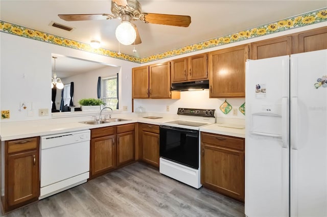 1148 Monroe Ave, Saint Cloud, FL 34769 - kitchen featuring white appliances, a sink, under cabinet range hood, and brown cabinetry