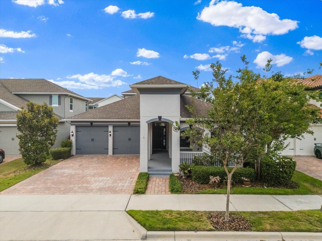 view of front of home with a garage, stucco siding, a porch, and decorative driveway