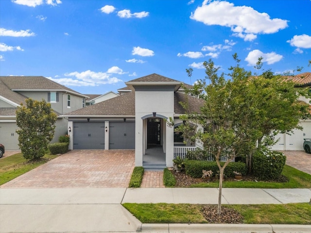 view of front of home with a garage, stucco siding, a porch, and decorative driveway