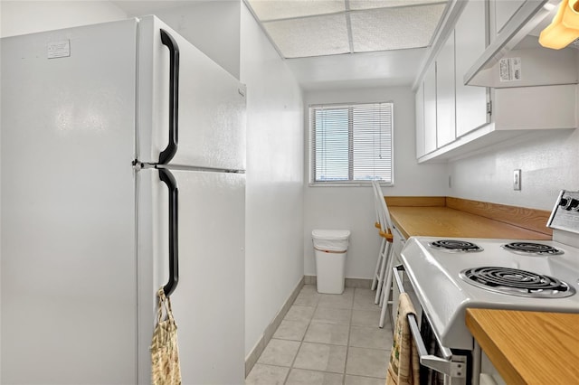 2465 S Washington Ave Unit A402, Titusville, FL 32780 - kitchen with white appliances, light tile patterned floors, baseboards, under cabinet range hood, and white cabinetry