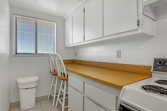 2465 S Washington Ave Unit A402, Titusville, FL 32780 - kitchen with white electric range oven, white cabinetry, light countertops, light tile patterned floors, and baseboards