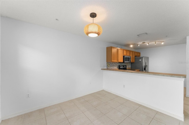 435 Tradition Ln, Winter Springs, FL 32708 - kitchen featuring backsplash, appliances with stainless steel finishes, a textured ceiling, a peninsula, and brown cabinetry