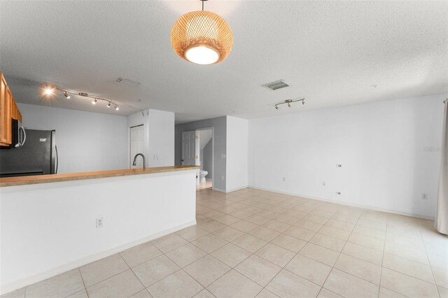 435 Tradition Ln, Winter Springs, FL 32708 - unfurnished living room with light tile patterned floors, a textured ceiling, a sink, visible vents, and track lighting
