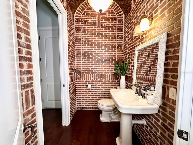 1570 Oakford Rd, Sarasota, FL 34240 - bathroom with brick wall, toilet, and hardwood / wood-style flooring