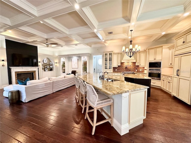 1570 Oakford Rd, Sarasota, FL 34240 - kitchen featuring cream cabinetry, appliances with stainless steel finishes, a kitchen island with sink, a sink, and dark wood finished floors